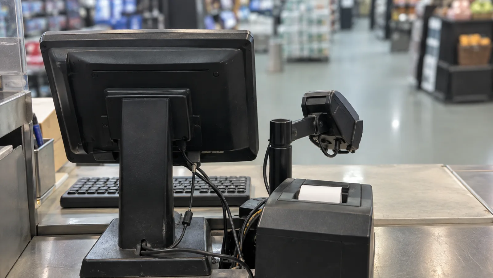 Kassaterminal med skärm, kortläsare och kvittoskrivare sedd från personalens sida av disken